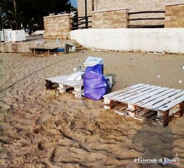 Bivaccano sulla spiaggia di Trani e sfilano due bancali dall'arredo urbano per sedersi: abbandonati sulla sabbia con i rifiuti